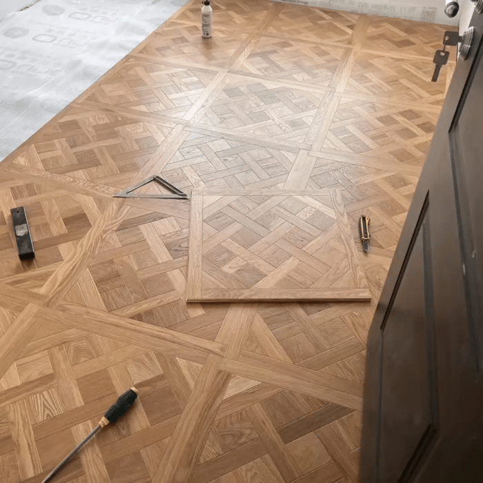 Solid oak Versailles flooring installed in interior space, showing geometric parquet panel layout and natural wood grain
