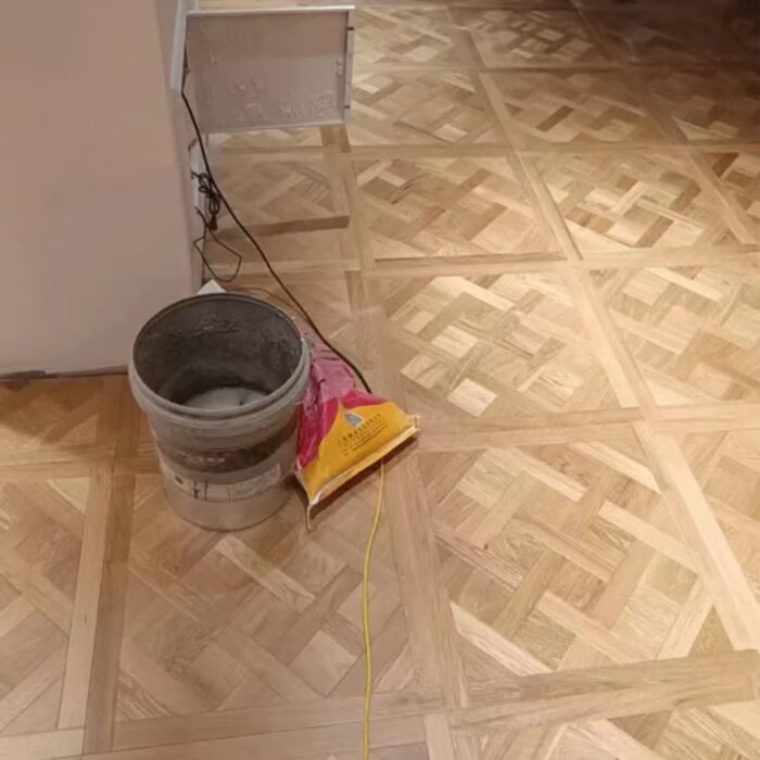 Solid oak Versailles flooring installed in interior space, showing geometric parquet panel layout and natural wood grain