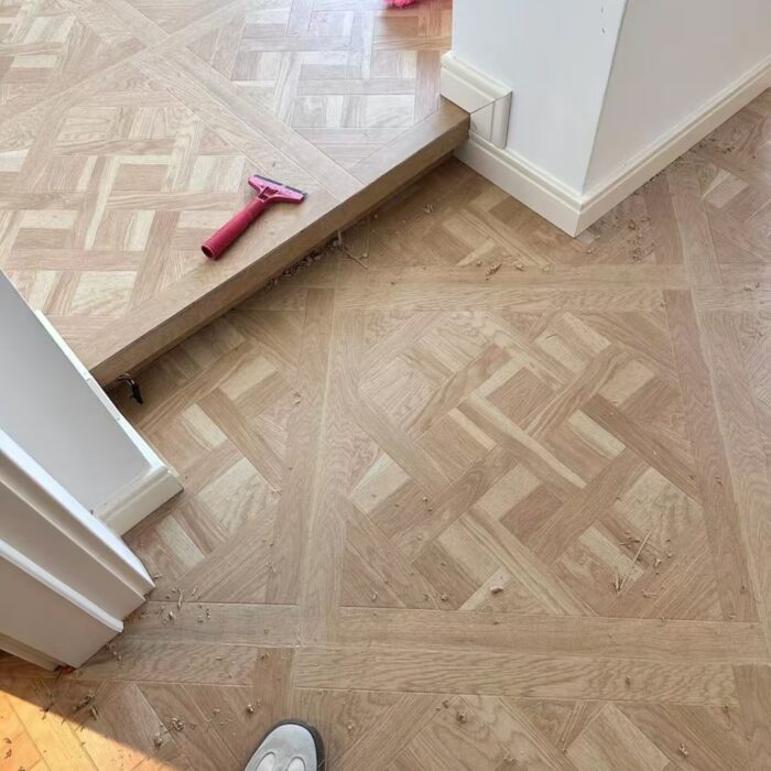Solid oak Versailles flooring installed in interior space, showing geometric parquet panel layout and natural wood grain